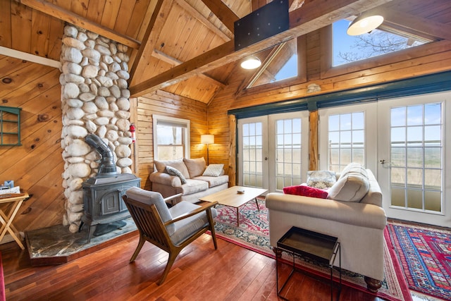 living room featuring wooden ceiling, wooden walls, a wood stove, beamed ceiling, and french doors