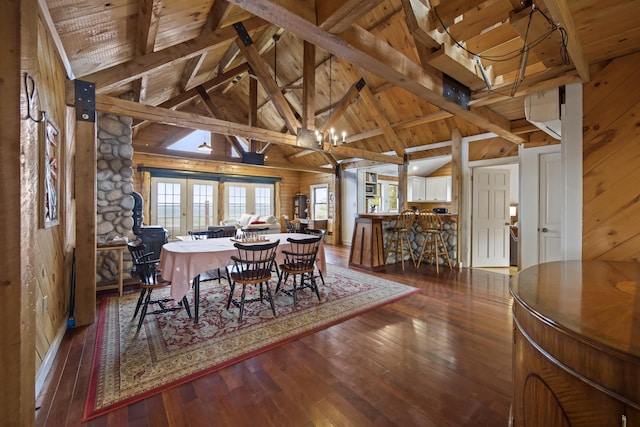 dining space with beam ceiling, a chandelier, wooden ceiling, and wooden walls