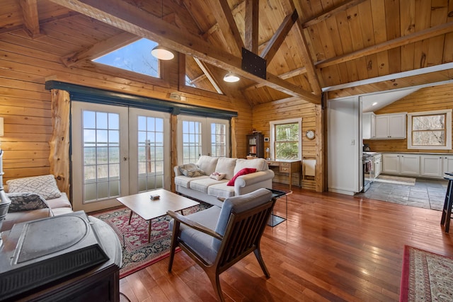 living room with beam ceiling, french doors, wooden ceiling, and wood walls