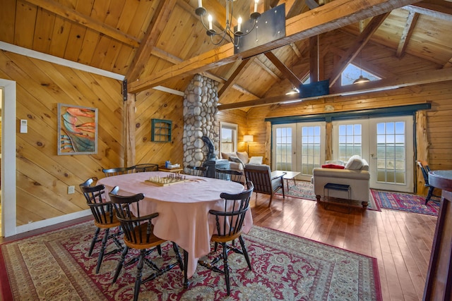 dining area featuring beam ceiling, french doors, wood ceiling, and wooden walls