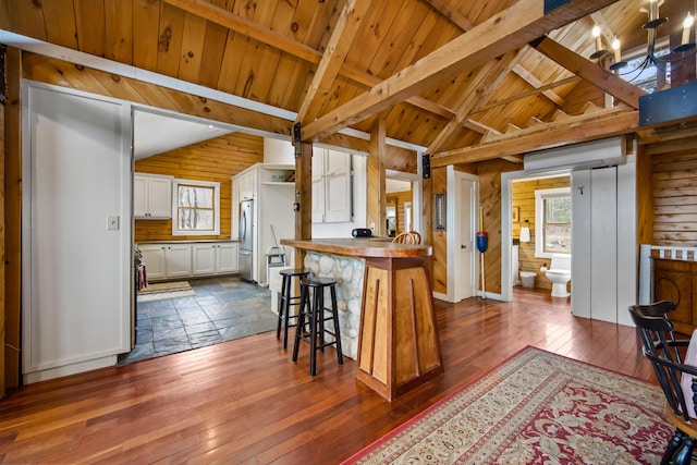 kitchen with stainless steel fridge, wooden walls, wooden counters, white cabinetry, and a wall mounted air conditioner