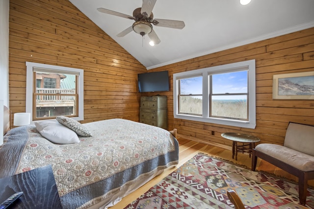 bedroom with lofted ceiling, wooden walls, hardwood / wood-style floors, and ceiling fan