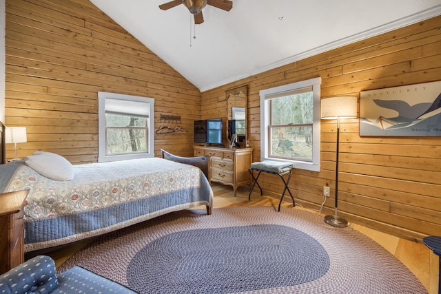 bedroom featuring lofted ceiling, wooden walls, multiple windows, and ceiling fan