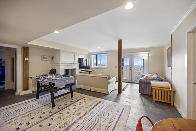 recreation room with french doors, a large fireplace, and crown molding