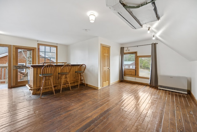 bar featuring dark wood-type flooring, lofted ceiling, and radiator