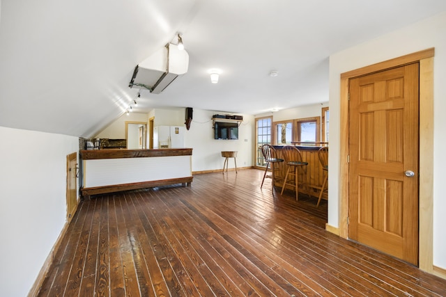 interior space featuring white refrigerator with ice dispenser, dark wood-type flooring, and vaulted ceiling