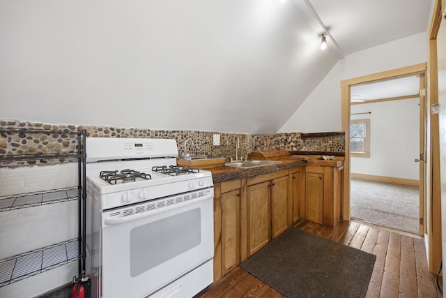 kitchen with vaulted ceiling, white range with gas stovetop, dark hardwood / wood-style floors, and sink