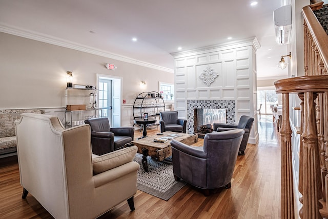 living room featuring crown molding, wood-type flooring, and a tile fireplace