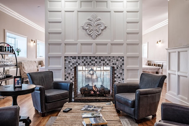 living room with wood-type flooring, crown molding, and a tiled fireplace