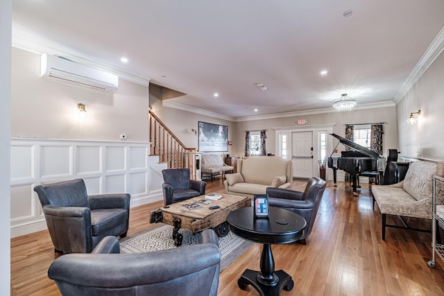 living room with an inviting chandelier, crown molding, light hardwood / wood-style flooring, and a wall mounted air conditioner