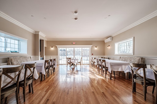 dining space featuring crown molding, light hardwood / wood-style floors, plenty of natural light, and a wall mounted air conditioner