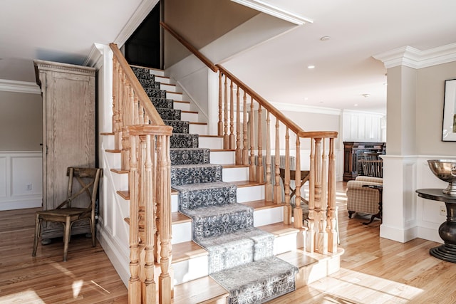 staircase with wood-type flooring and ornamental molding