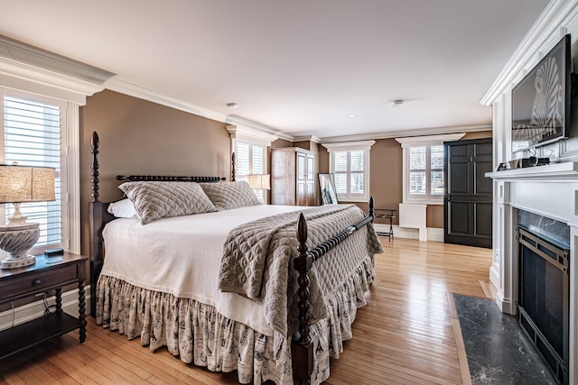 bedroom with a premium fireplace, ornamental molding, and hardwood / wood-style floors