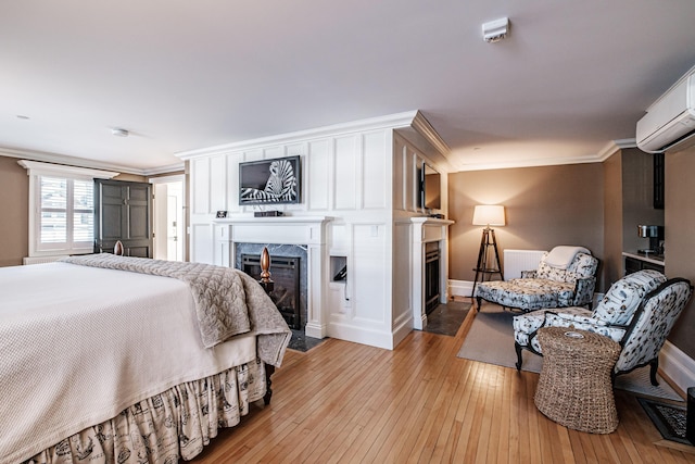 bedroom featuring an AC wall unit, crown molding, and light hardwood / wood-style floors