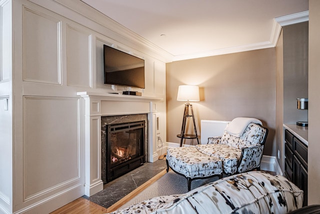 sitting room featuring hardwood / wood-style floors, a high end fireplace, and ornamental molding