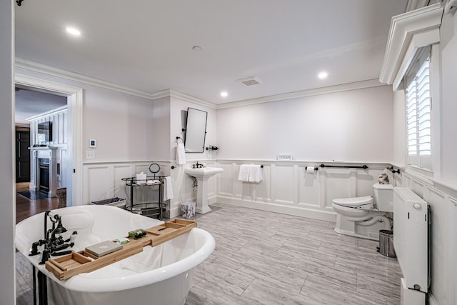 bathroom with toilet, radiator heating unit, crown molding, a washtub, and sink