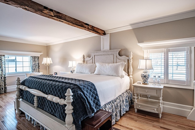 bedroom with beam ceiling, wood-type flooring, and crown molding