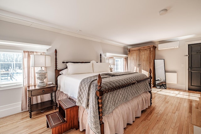 bedroom featuring light wood-type flooring, a wall mounted AC, crown molding, and radiator heating unit