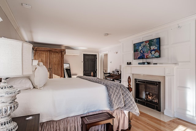 bedroom with an AC wall unit, crown molding, and light hardwood / wood-style flooring