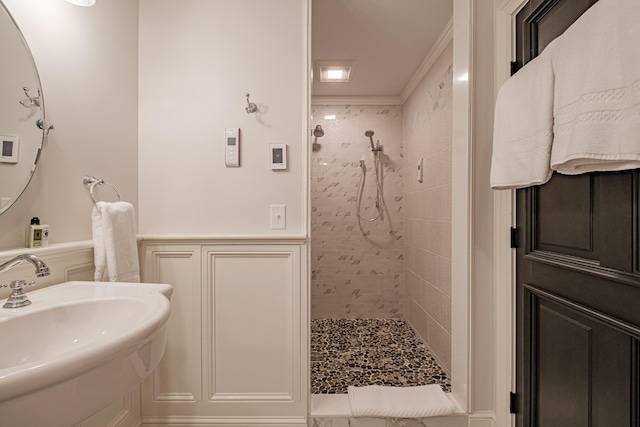 bathroom with sink, crown molding, and tiled shower