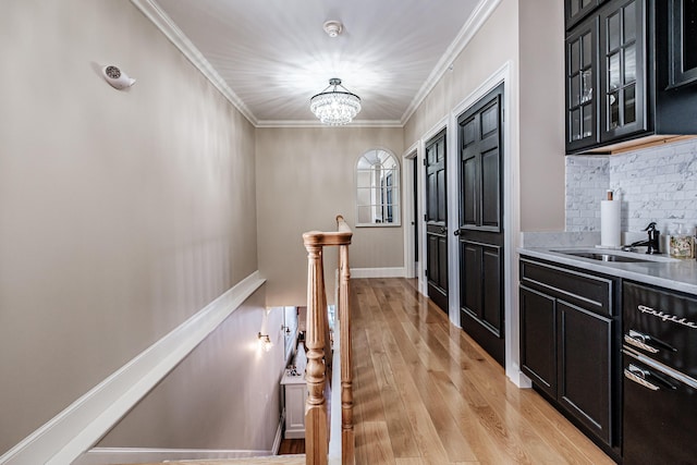 hall with a chandelier, ornamental molding, light hardwood / wood-style flooring, and sink