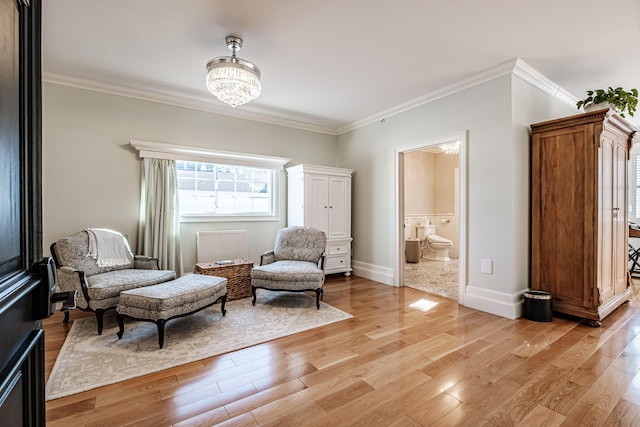 sitting room featuring light wood-type flooring, crown molding, and a notable chandelier