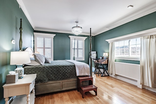 bedroom featuring radiator, ornamental molding, light wood-type flooring, and a notable chandelier