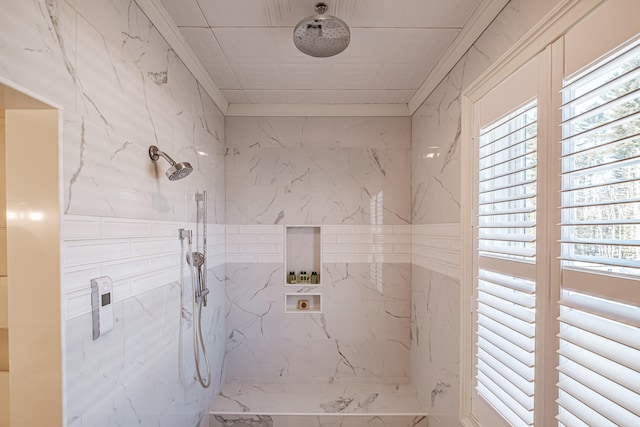 bathroom with ornamental molding and a tile shower