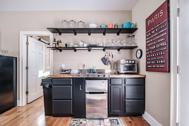 bar featuring black refrigerator, light hardwood / wood-style flooring, and a barn door