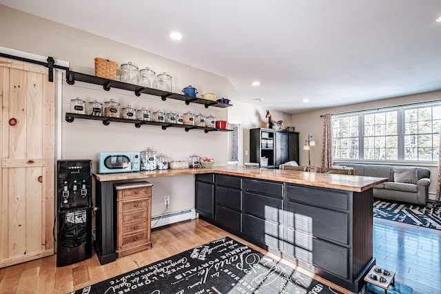 kitchen featuring light wood-type flooring, a barn door, kitchen peninsula, and a baseboard heating unit