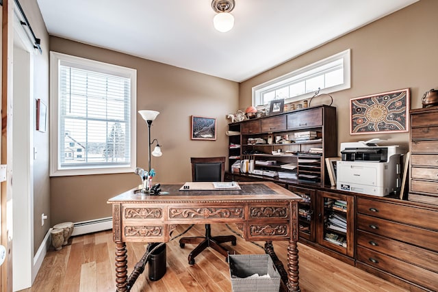 office space featuring a baseboard heating unit, a wealth of natural light, and light hardwood / wood-style floors