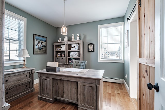 office area with light hardwood / wood-style floors, a barn door, plenty of natural light, and a baseboard radiator