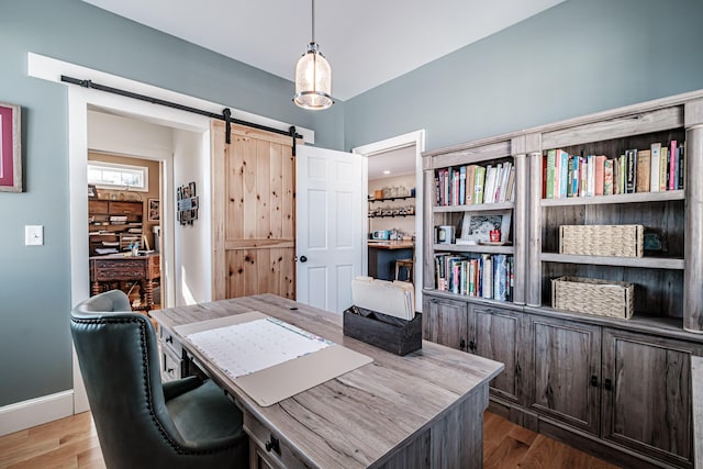 home office featuring hardwood / wood-style flooring and a barn door