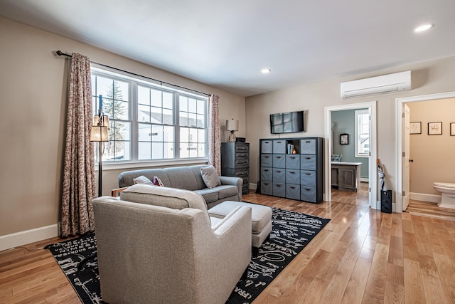 living room with a baseboard heating unit, hardwood / wood-style flooring, and a wall mounted air conditioner