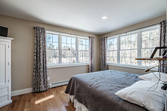 bedroom with a baseboard radiator and light hardwood / wood-style flooring