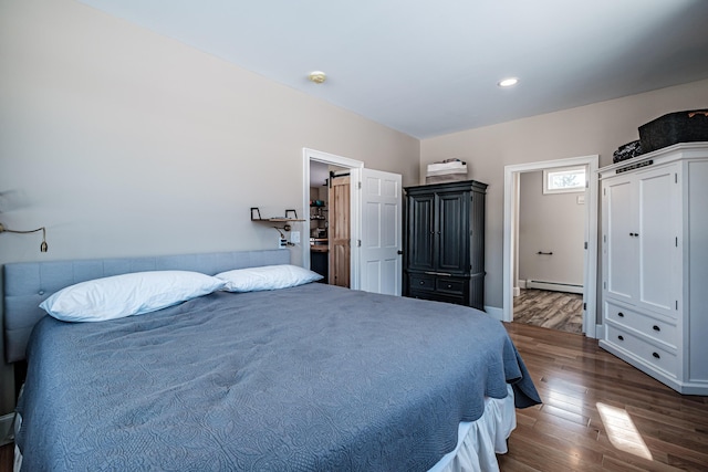 bedroom with a baseboard heating unit and dark hardwood / wood-style floors