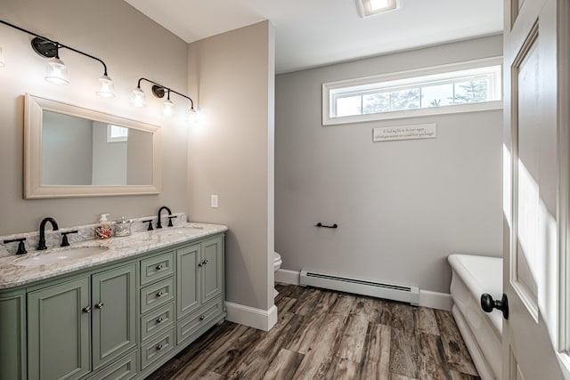 bathroom featuring toilet, vanity, a baseboard heating unit, a bath, and wood-type flooring