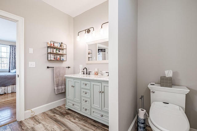 bathroom with toilet, hardwood / wood-style flooring, and vanity