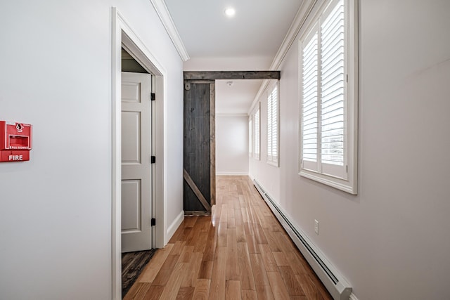 hallway with a baseboard radiator, wood-type flooring, ornamental molding, and a barn door