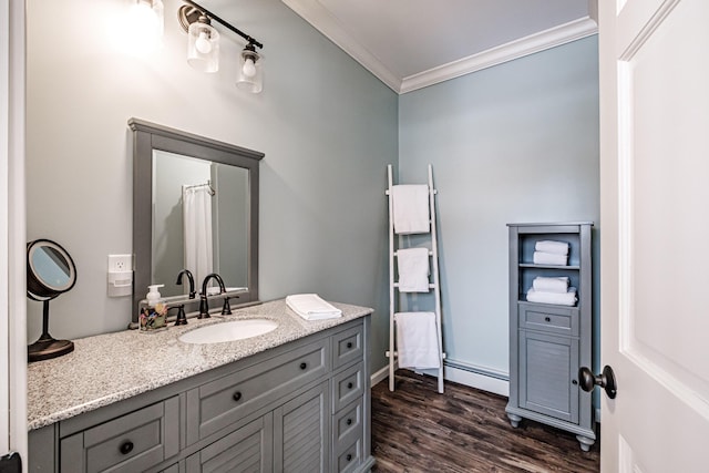 bathroom featuring hardwood / wood-style flooring, baseboard heating, vanity, and ornamental molding