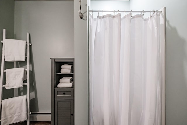 bathroom with curtained shower and a baseboard heating unit