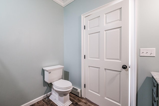 bathroom with toilet, vanity, wood-type flooring, crown molding, and baseboard heating