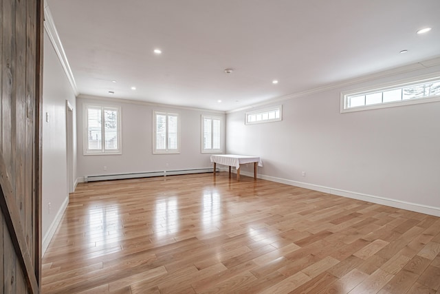 basement with a baseboard heating unit, crown molding, and light hardwood / wood-style floors