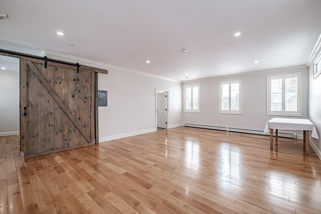 empty room featuring light hardwood / wood-style floors, a baseboard heating unit, crown molding, and a barn door