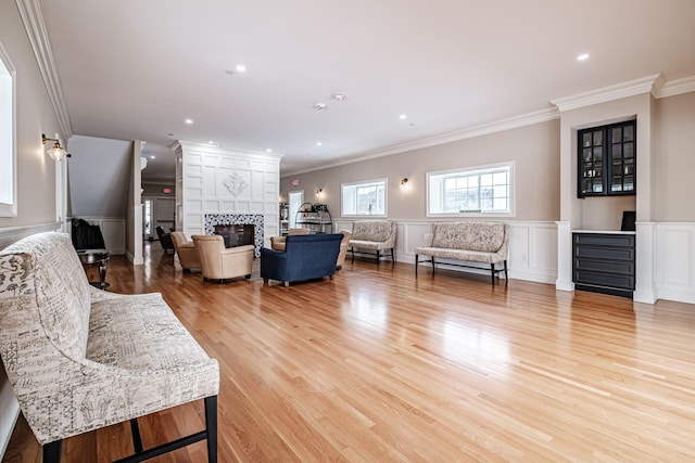 living room featuring crown molding, a fireplace, and light hardwood / wood-style flooring