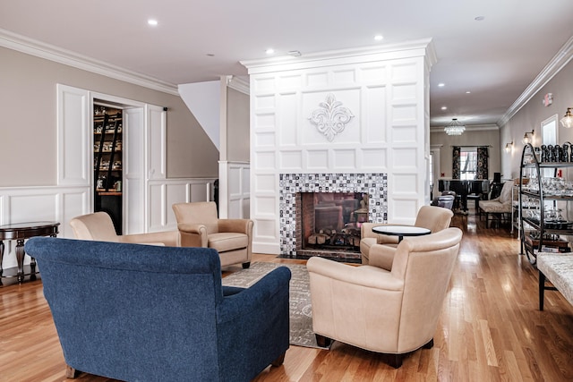 living room with light wood-type flooring, ornamental molding, and a tile fireplace