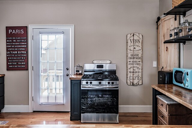 kitchen featuring a barn door, stainless steel gas range oven, and light hardwood / wood-style floors