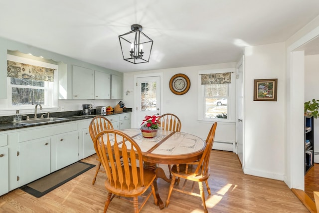 kitchen featuring an inviting chandelier, a baseboard heating unit, light wood-type flooring, hanging light fixtures, and sink