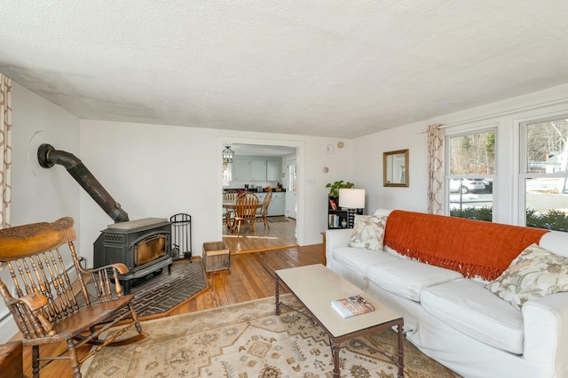 living room with a textured ceiling, a wood stove, and hardwood / wood-style floors