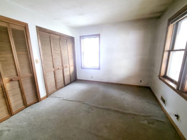 unfurnished bedroom with multiple closets and carpet flooring